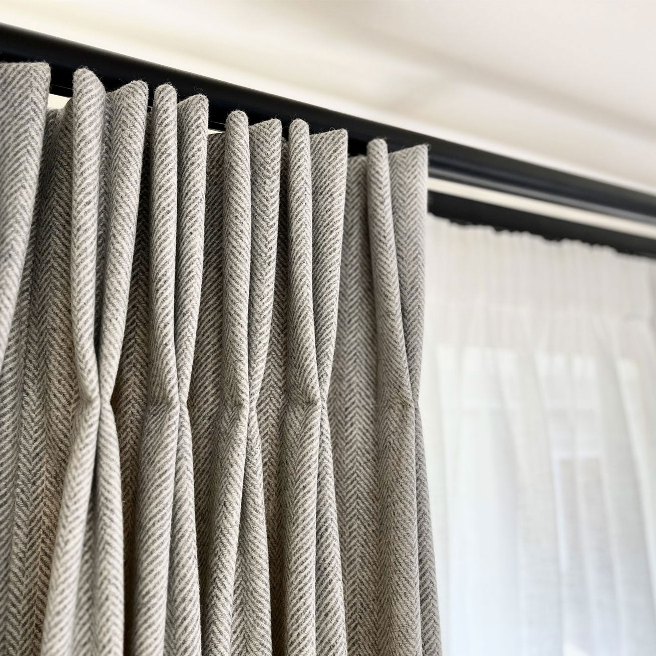 Black double curtain track with gray herringbone wool curtains.