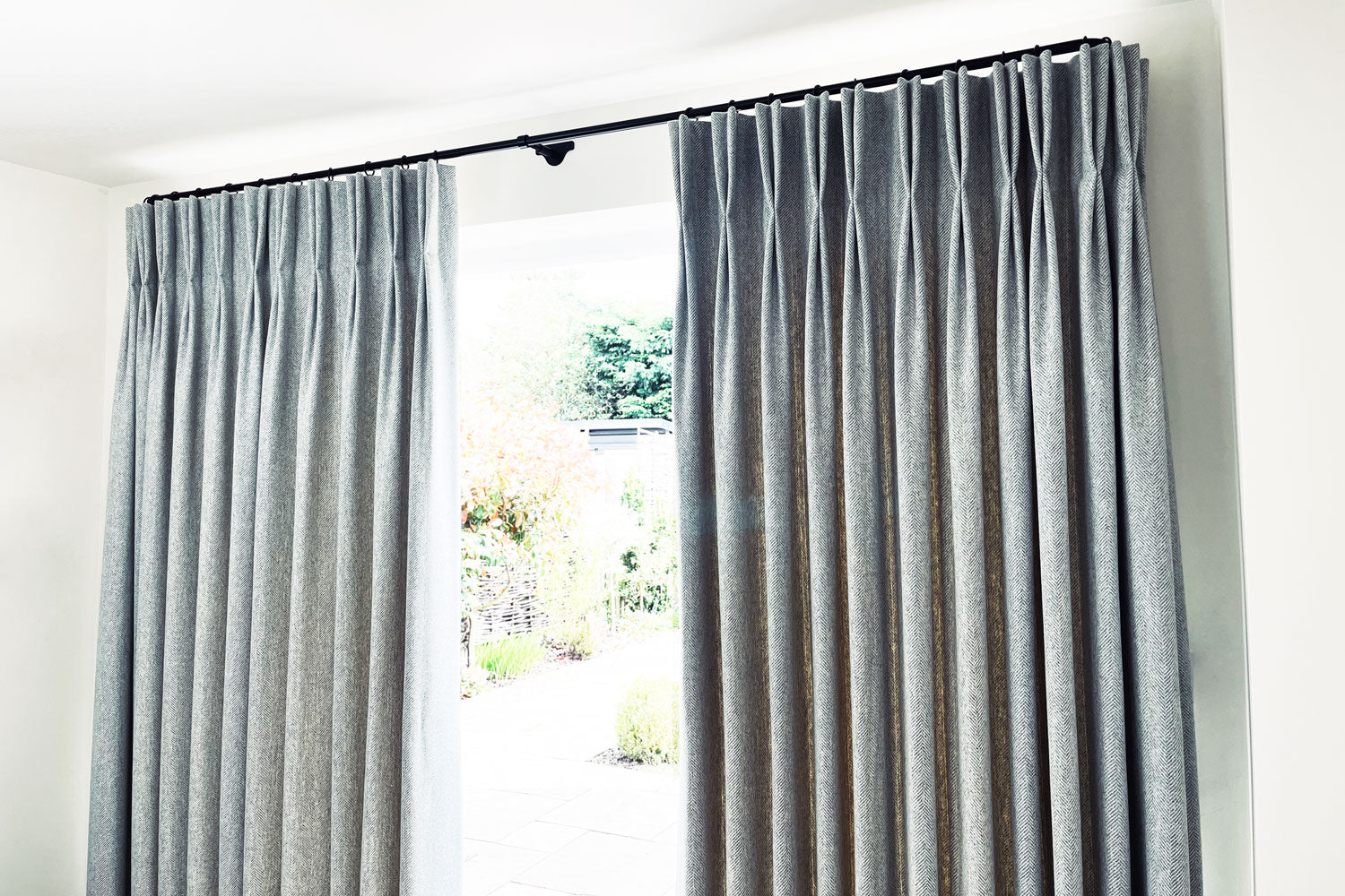 Pair of heavy wool curtains on a French curtain pole at patio doors